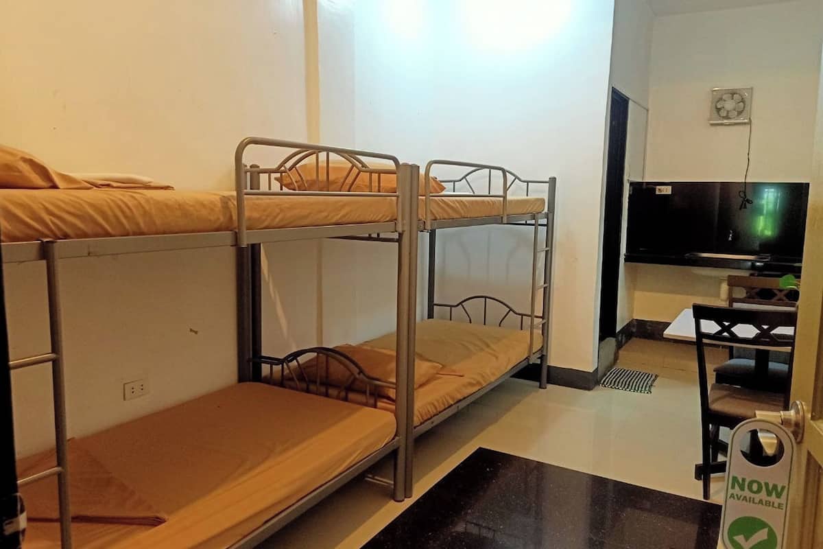 Un dormitorio con literas, un escritorio, una silla, un televisor y un cartel que dice 'Ahora Disponible'.