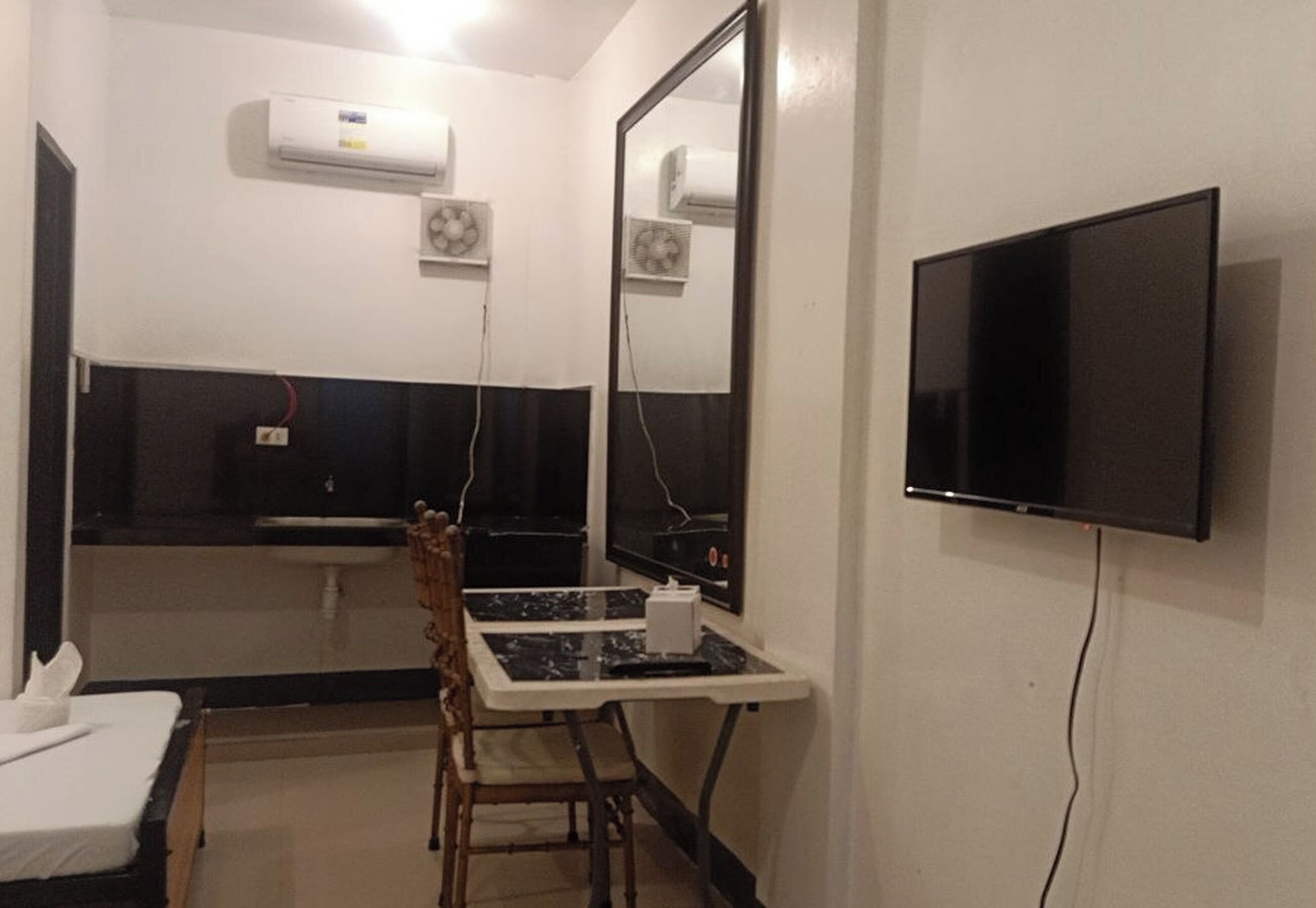 Une chambre d’hôtel équipée d’un lit, d’un bureau avec une chaise, d’une télévision, d’un miroir et d’un appareil de climatisation.