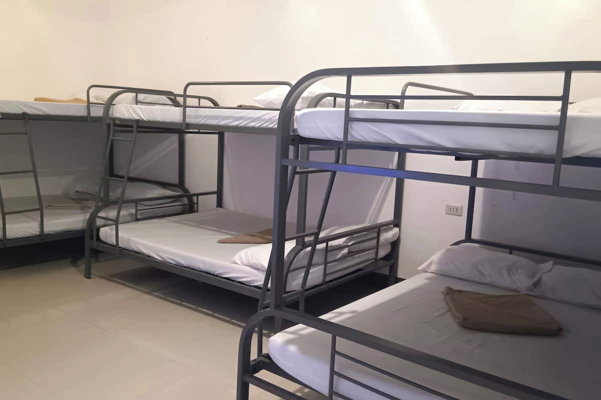 Un dormitorio con literas, cada una con colchón y almohada.
