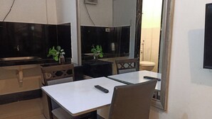 A compact kitchen with a sink, a small table, and chairs. There is a plant on the table and a remote control on the table. - Hotel Villarte Fort Pampanga (San Fernando)