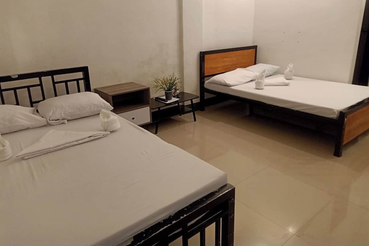Una habitación de hotel con dos camas individuales, una mesita de noche con una planta y una lámpara.