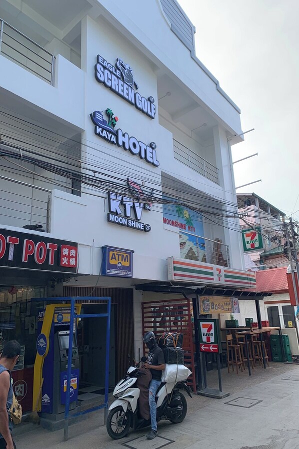 Un immeuble sur lequel on peut voir une enseigne indiquant « Eagle Screen Gold Kaya Hotel », « KTV Moonshine 2 » et un magasin « 7-Eleven ».