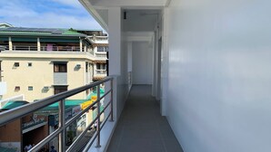 A narrow corridor with a metal railing on one side, leading to a door at the end. - Hotel Kaya Puerto Galera (Puerto Galera)