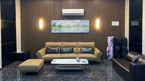 A modern lobby with a leather sofa, a coffee table, and a mounted TV. - Hotel Kaya Puerto Galera (Puerto Galera)