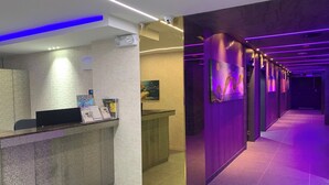 A modern hotel reception area with a reception desk, a digital display, and a wall-mounted security camera. - Hotel Kaya Puerto Galera (Puerto Galera)