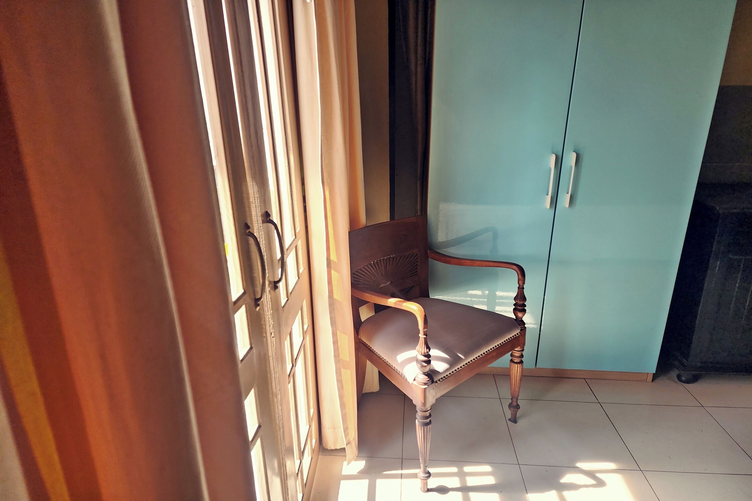 A room with a wooden chair, a light blue wardrobe, and a partially open door.