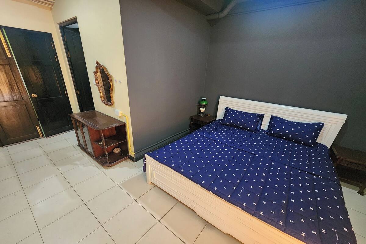 Une chambre à coucher avec un lit, une table de chevet, une commode et un miroir.