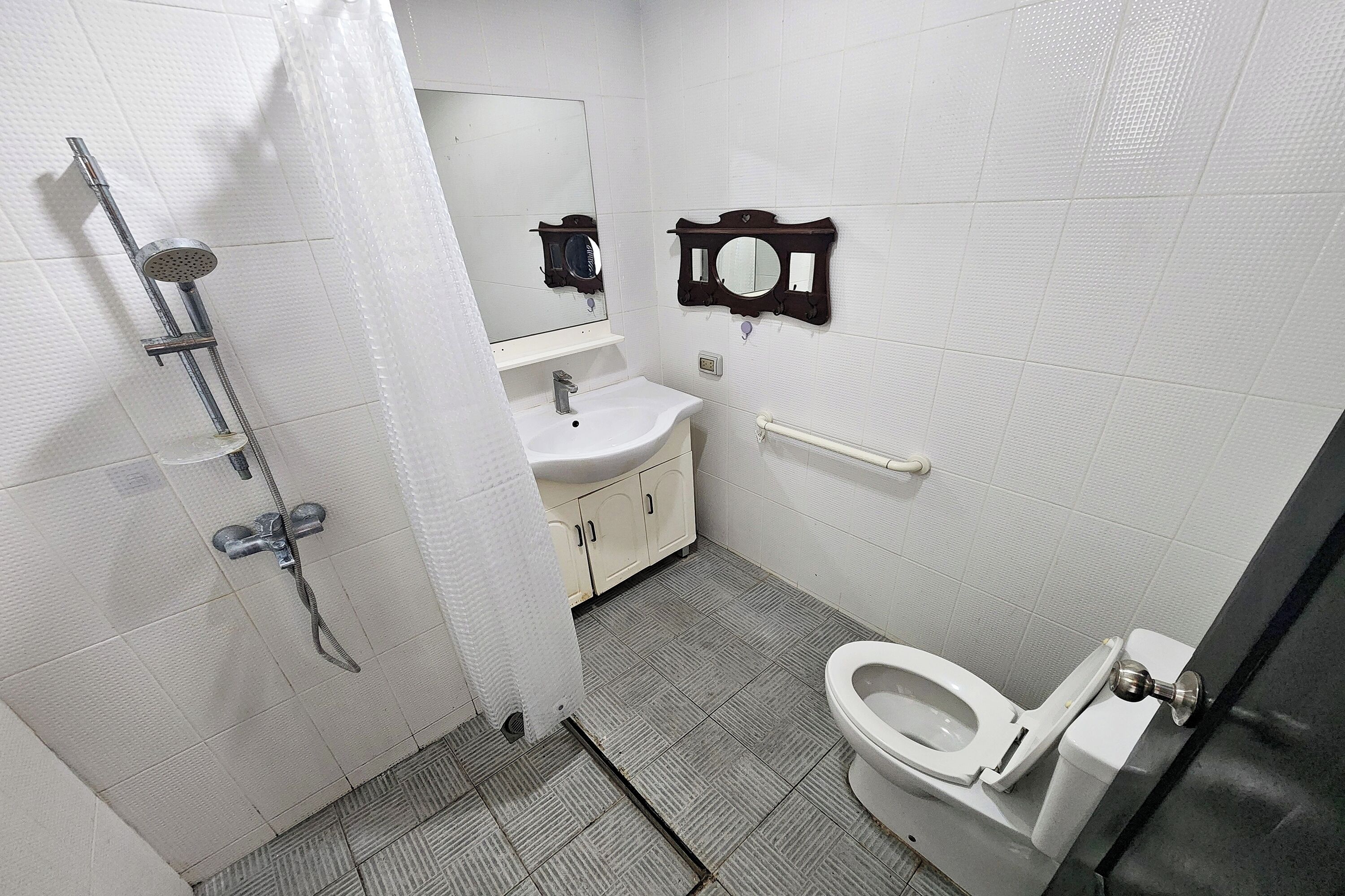 Un baño con ducha, lavamanos, espejo e inodoro.
