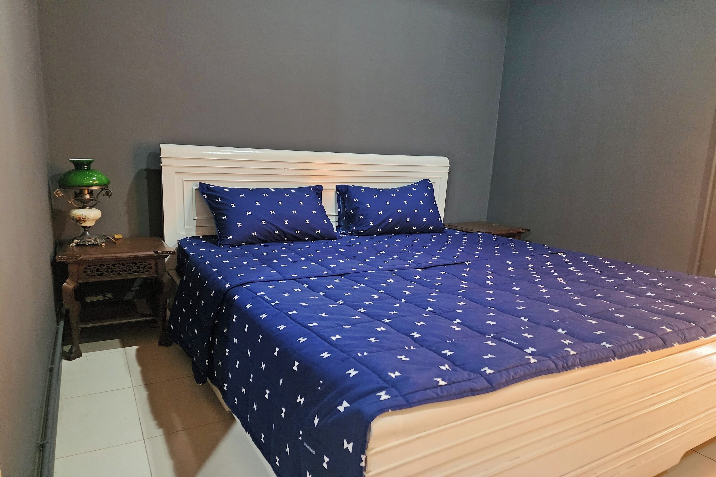 A bedroom with a bed, a nightstand, and a green lamp.