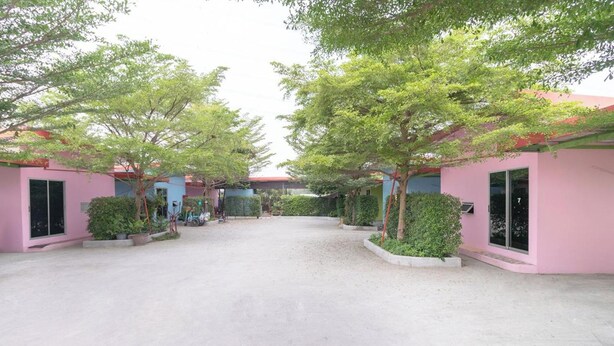 A courtyard with pink buildings, trees, and a gravel path.