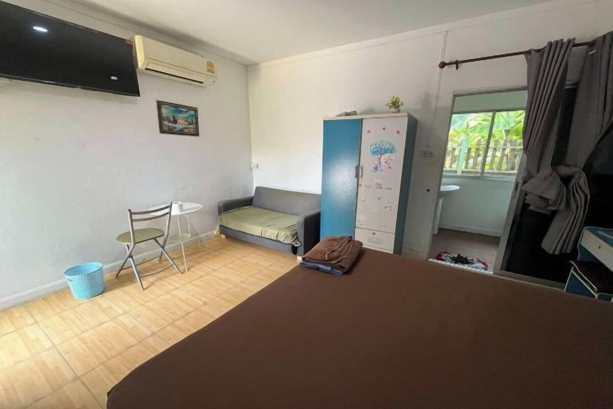Una habitación con cama, una mesita, una silla, un armario y una ventana con cortinas.