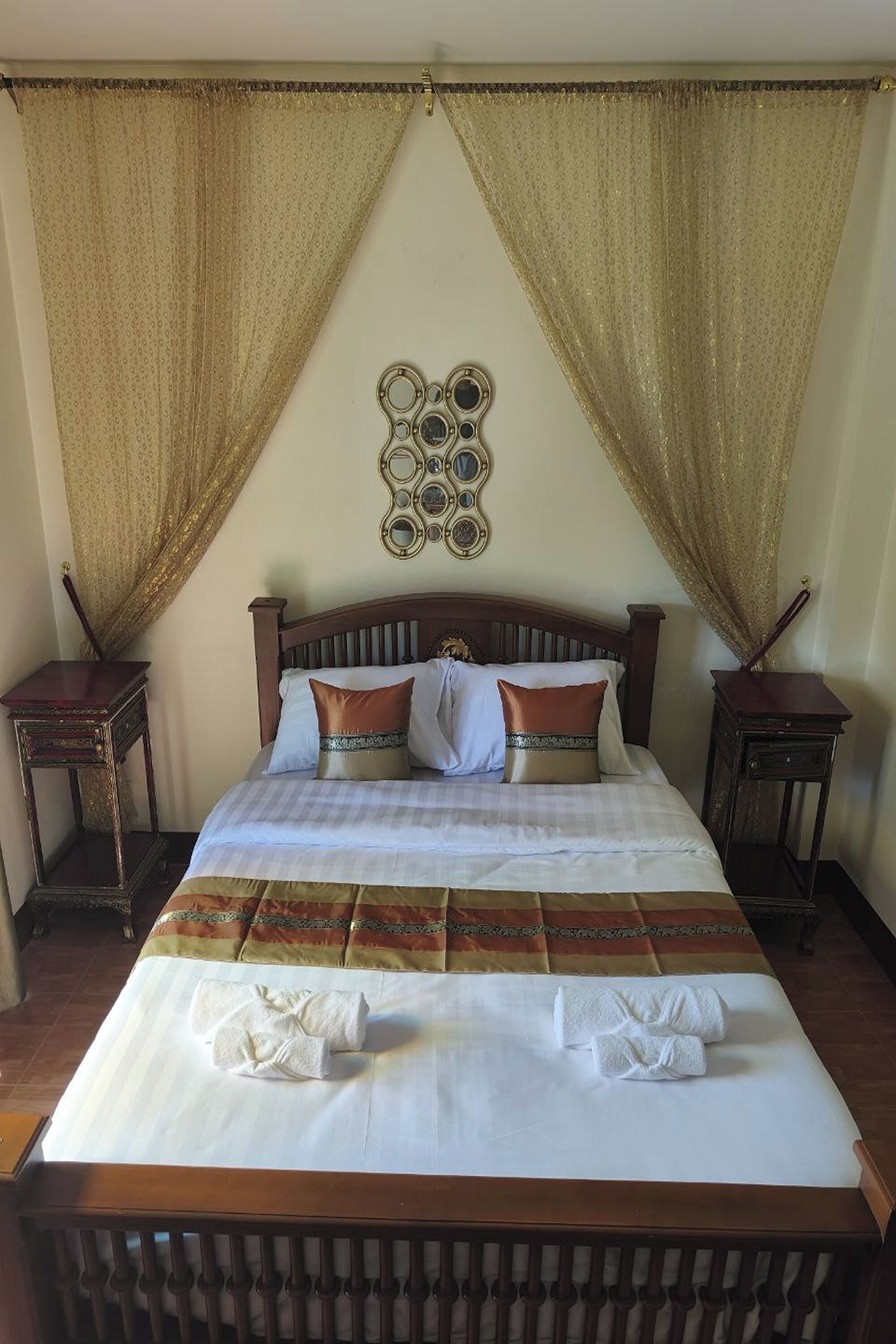 A neatly made bed with white linens and two pillows, flanked by two nightstands with small tables.