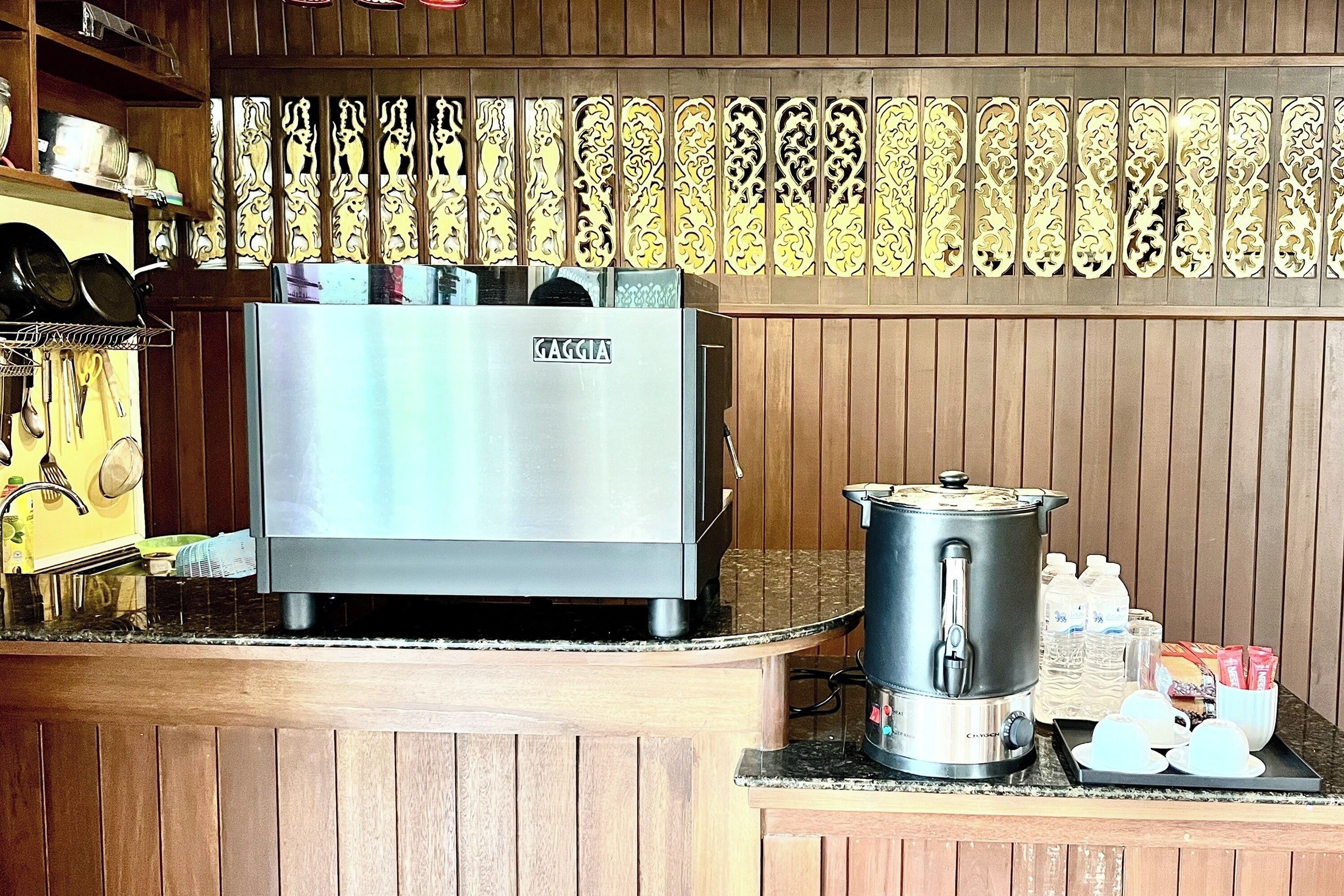 Una cocina equipada con una máquina de espresso Gaggia, una cafetera y una bandeja con tazas y un termo.