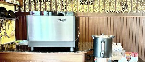 Una cocina equipada con una máquina de espresso Gaggia, una cafetera y una bandeja con tazas y un termo.