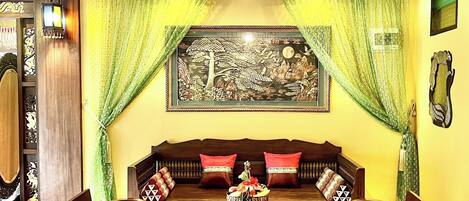 A traditional room with a sofa set, a dining table, and a chandelier.