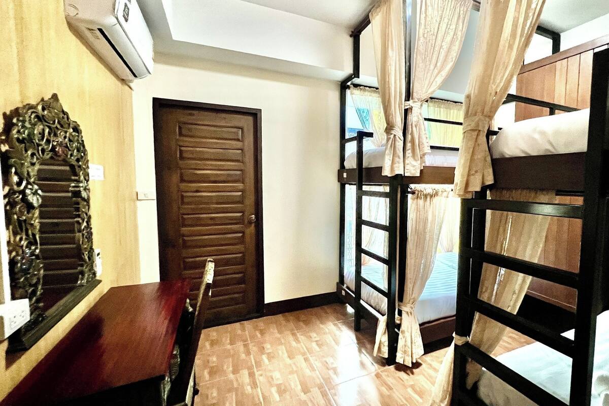 A room with a wooden door, a bed with a canopy, and a wooden table.