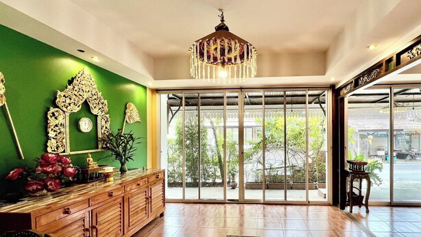 Un'ampia hall con una reception in legno, un lampadario decorativo e grandi porte scorrevoli in vetro che danno su una zona esterna.