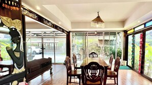 Un'area pranzo con un tavolo lungo e sei sedie, un lampadario e una vista attraverso ampie finestre.
