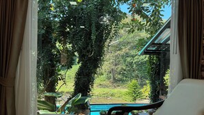Ein Zimmer mit Blick auf einen Swimmingpool, umgeben von üppiger Vegetation und einer Holzterrasse.