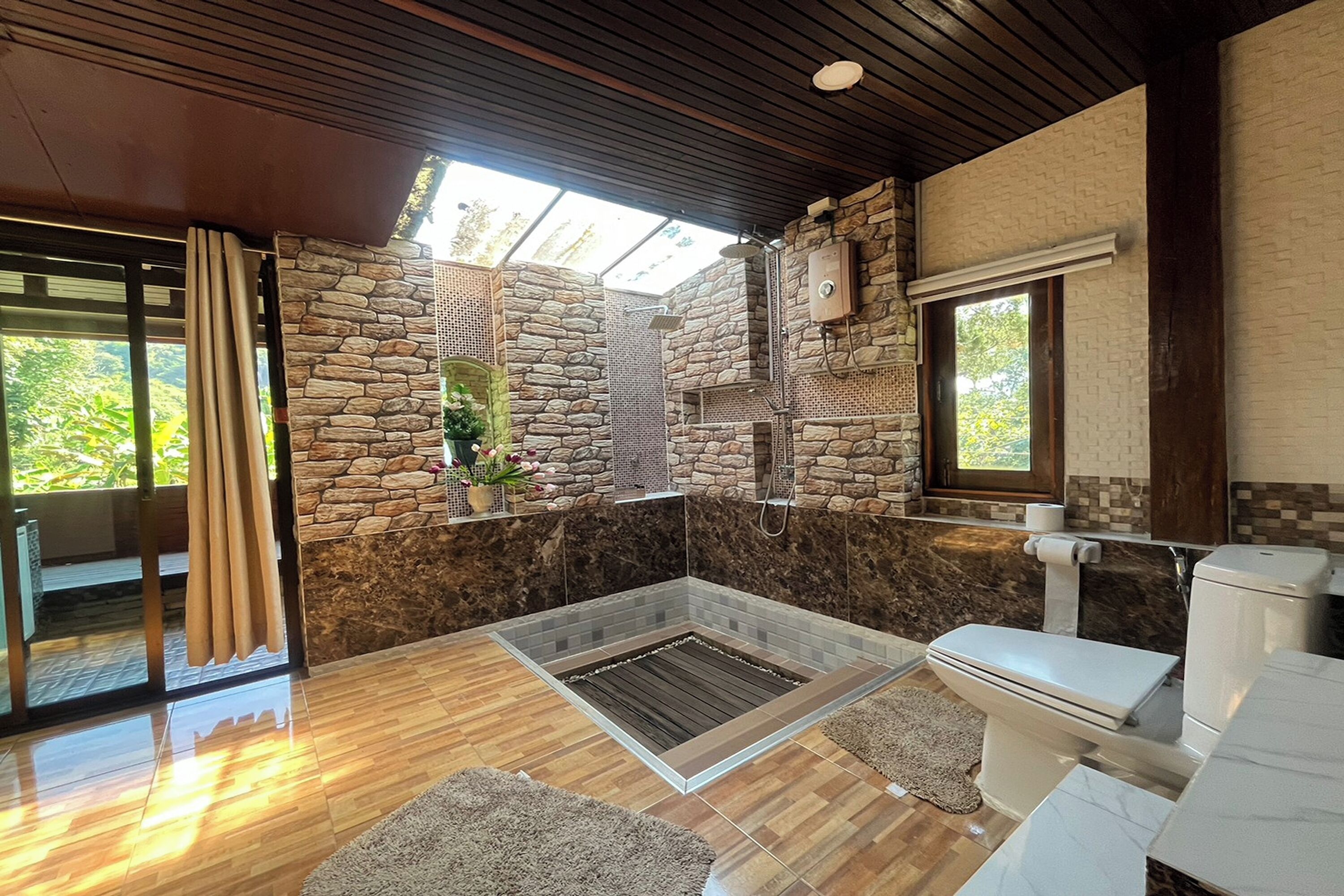 Ein Badezimmer mit Steinwand, Dusche und Toilette.