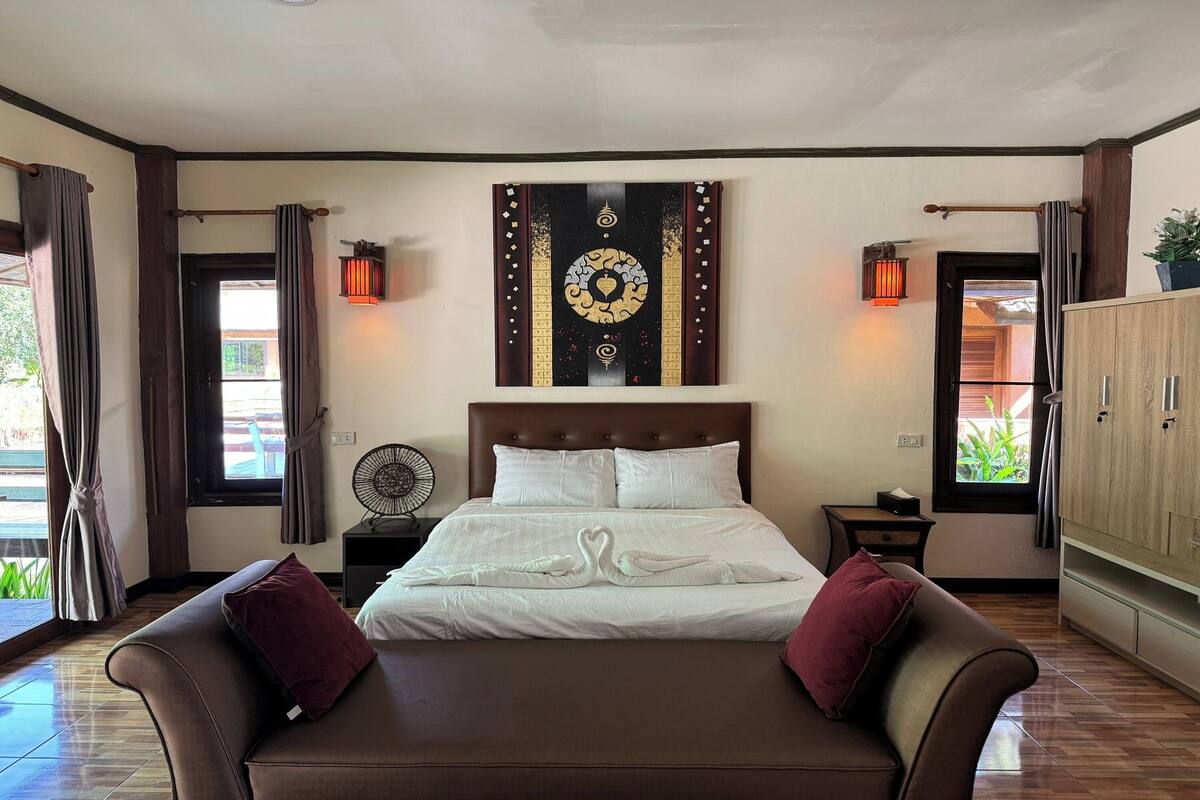 Une chambre d’hôtel avec un grand lit, deux tables de chevet, une œuvre d’art accrochée au mur et une vue par la fenêtre.