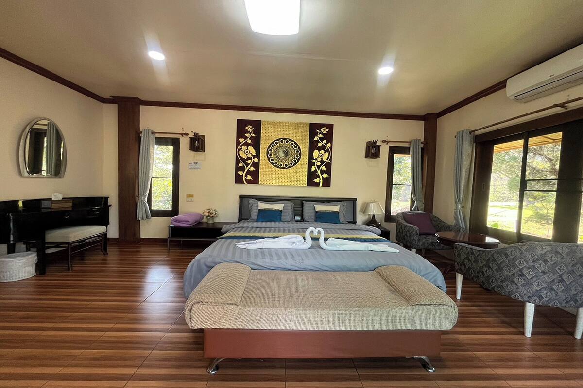 Une chambre spacieuse avec un grand lit, un piano et une vue sur l’extérieur par les fenêtres.