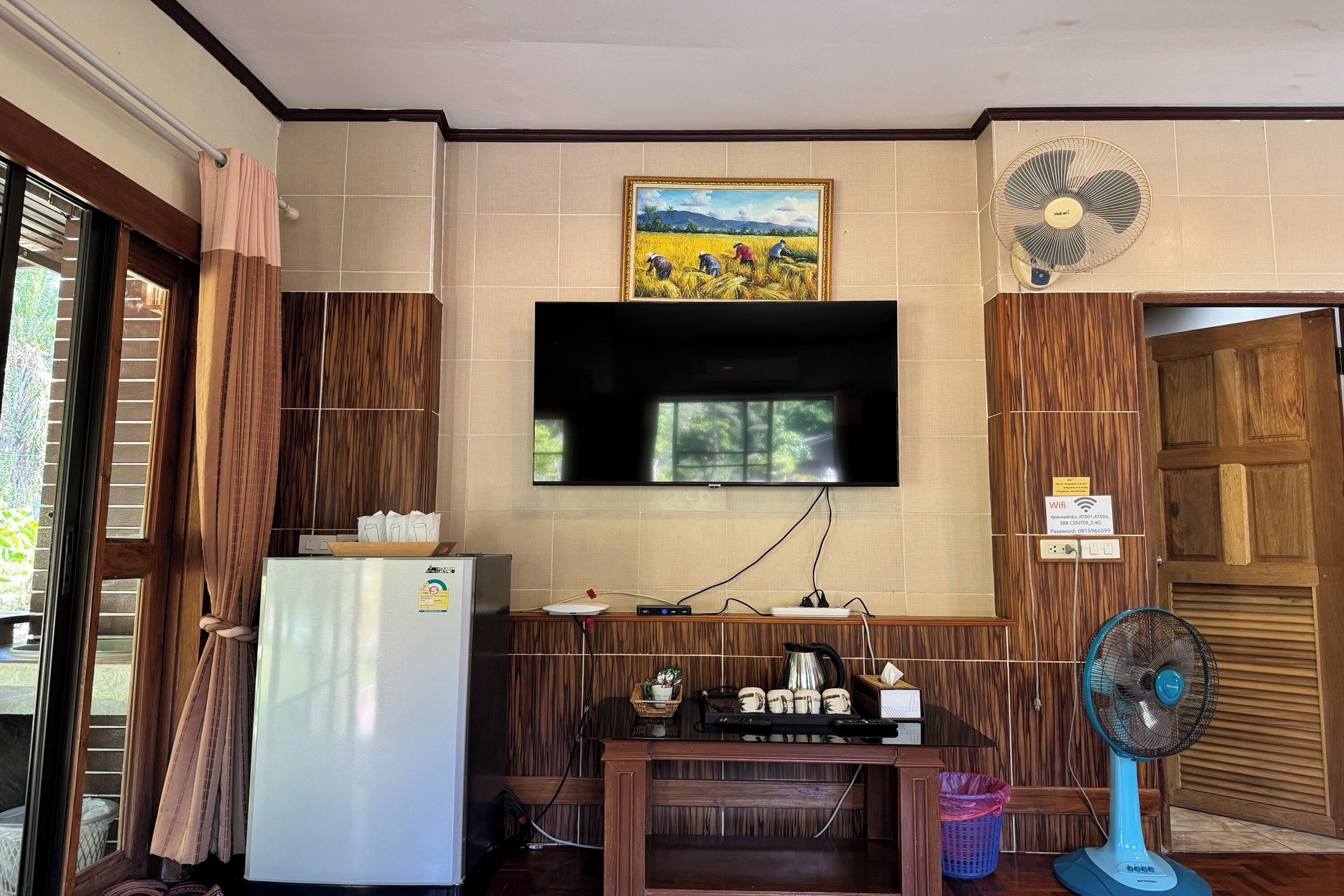 A compact kitchen with a refrigerator, a coffee maker, and a fan.