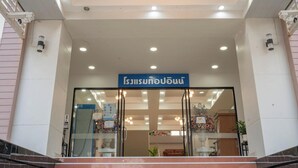 A hotel entrance with a sign in a foreign language, glass doors, and a staircase leading up.