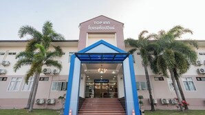 A hotel entrance with a blue archway, palm trees, and air conditioning units. - Top Inn Hotel (Maha Sarakham)