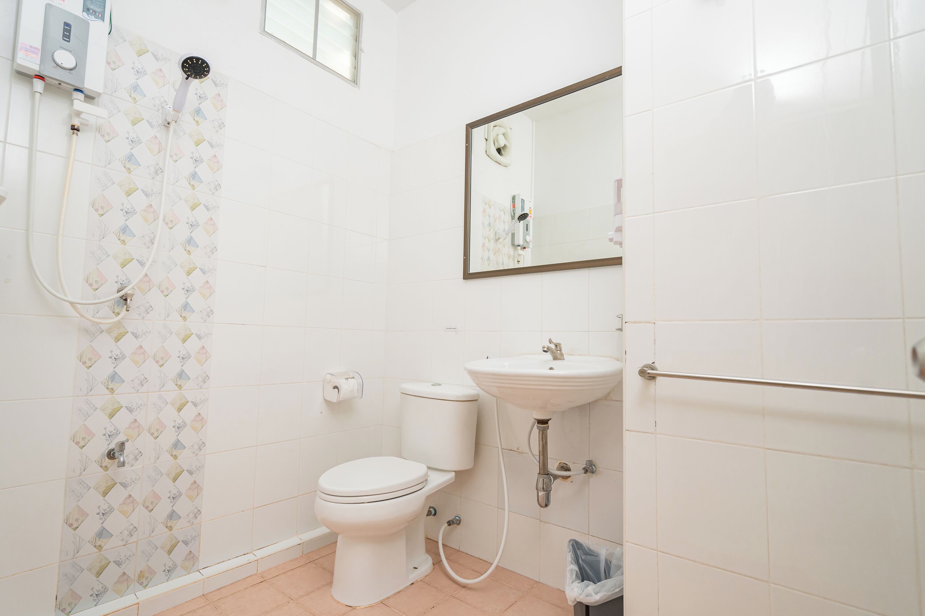 A bathroom with a toilet, sink, shower, and a mirror.