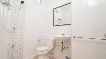 A bathroom with a toilet, sink, shower, and a mirror.