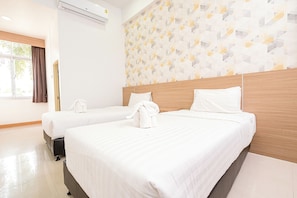 A hotel room with two beds, a wooden headboard, a patterned wall, and a window with curtains.