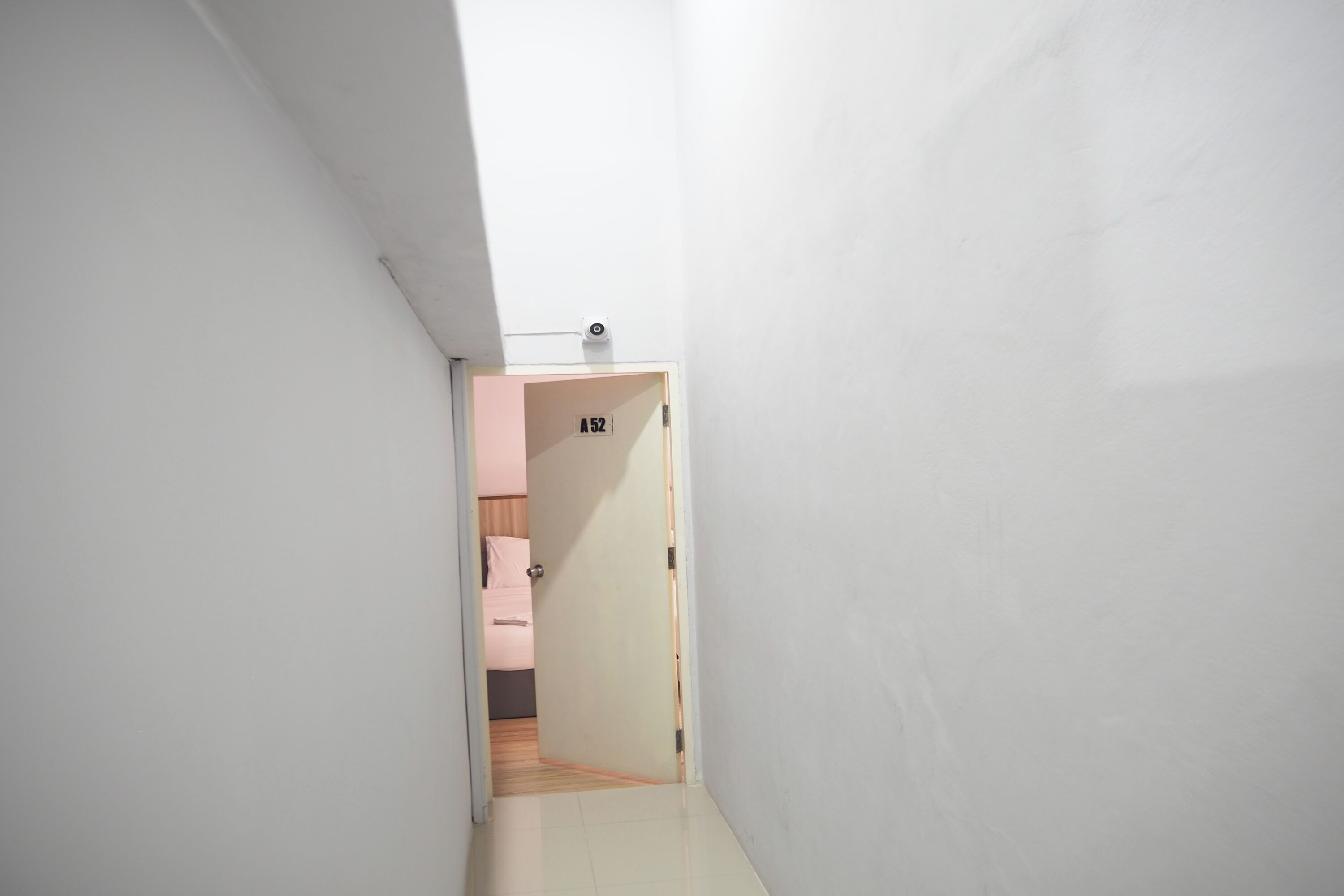 Um corredor estreito com uma porta identificada com 