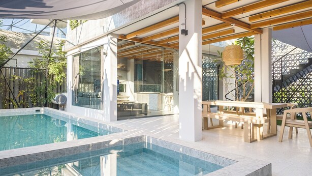 A modern outdoor pool area with a glass enclosure, wooden deck, and seating. - The Modern Pool Villa Hua Hin (Hua Hin)
