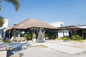 A building with a thatched roof, potted plants, and a Christmas tree.