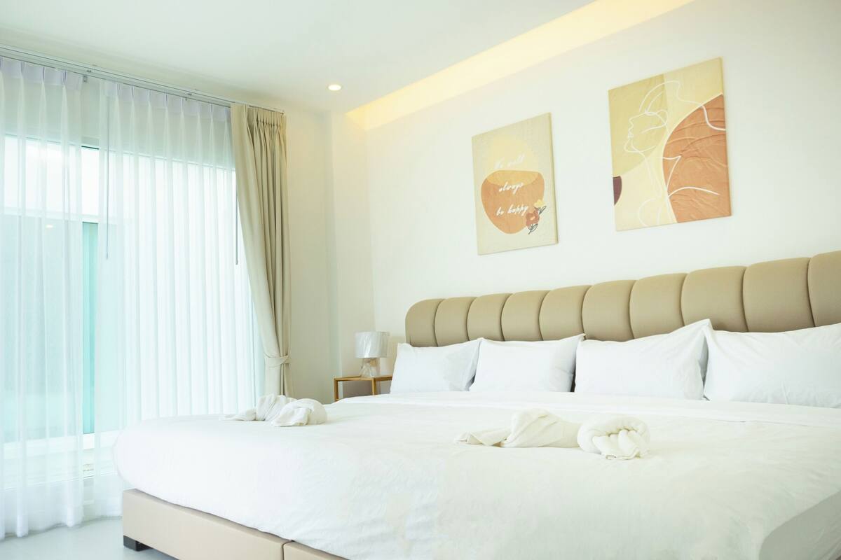 Une chambre d’hôtel moderne avec un grand lit, du linge de lit blanc et deux œuvres d’art murales.