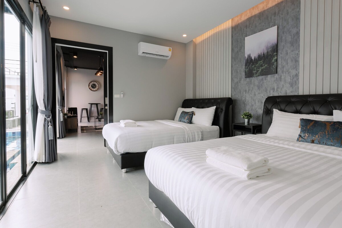 Een moderne hotelkamer met twee bedden, een groot raam en uitzicht op een zwembad.