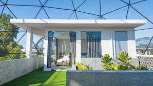 A modern house with a glass door leading to a bedroom, a balcony with artificial grass, and a geometric glass roof structure. - The Modern Pool Villa Hua Hin (Hua Hin)