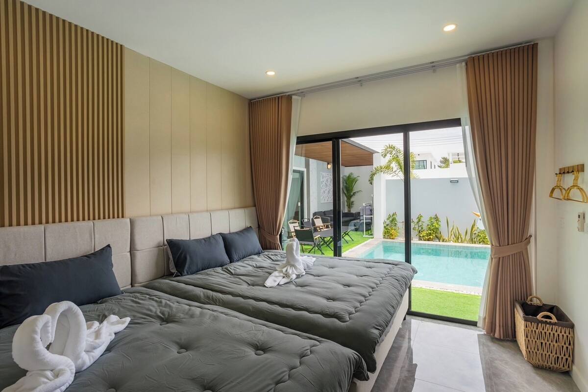Une chambre d’hôtel moderne avec deux lits, une grande fenêtre et une vue sur une piscine.