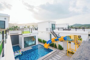 A rooftop pool area with a slide, a small inflatable unicorn float, and a view of the surrounding landscape.