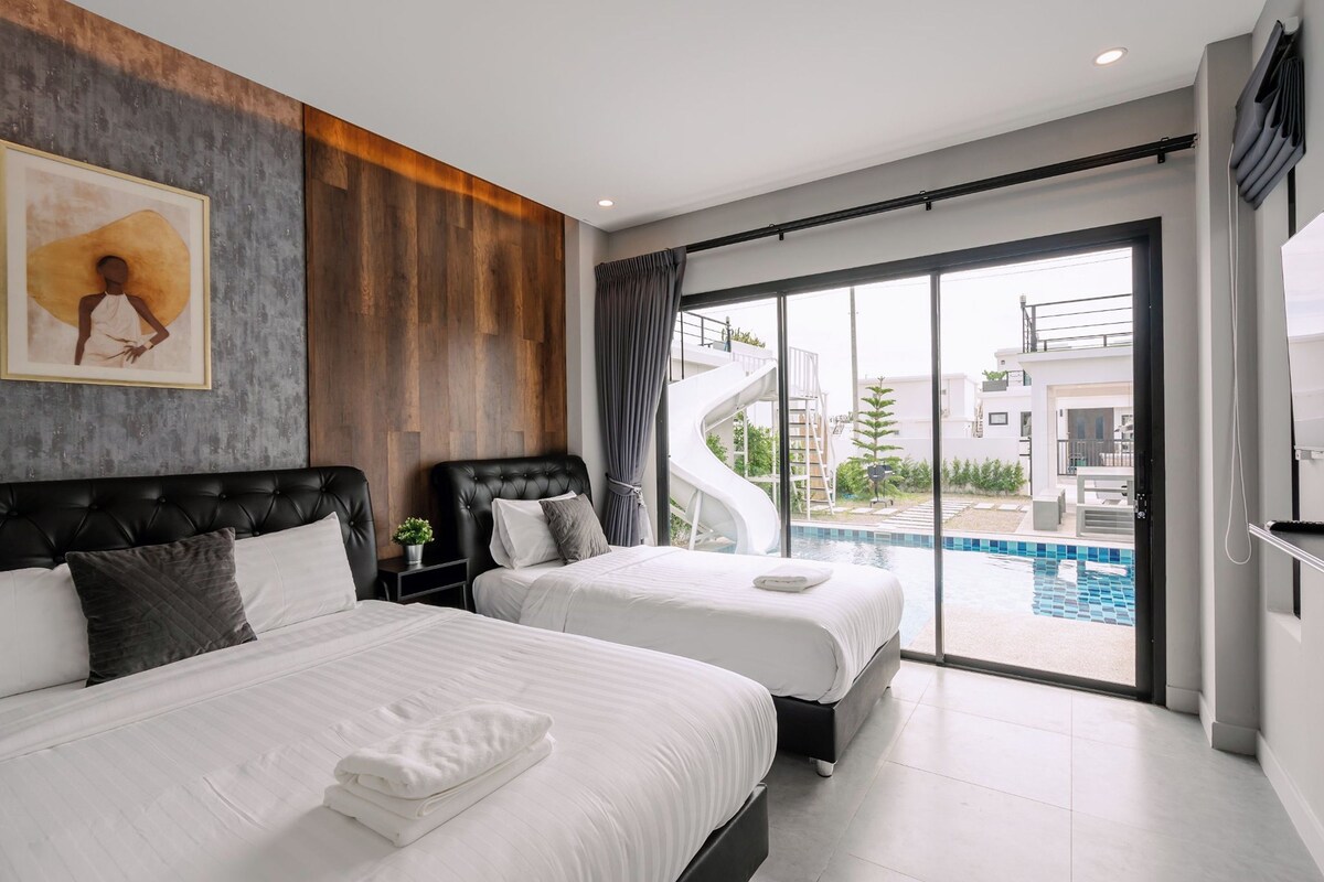 A modern hotel room with two beds, a large window with a view of a swimming pool and a spiral staircase.