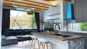 A modern kitchen with a marble countertop, wooden beams, and a large window. - The Modern Pool Villa Hua Hin (Hua Hin)
