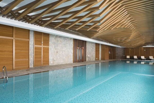 An indoor swimming pool with wooden paneling, stone walls, and a tiled floor. - YunDing Grand Hotel (Zhangjiakou)