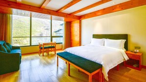 A bedroom with a large window, wooden beams, a bed, a bench, and a chair. - YunDing Grand Hotel (Zhangjiakou)