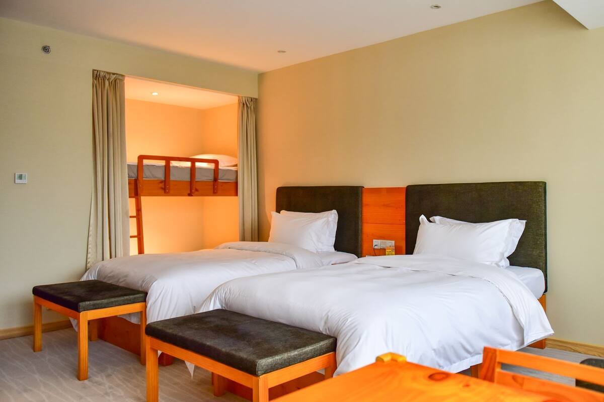 Una habitación de hotel con dos camas, un banco y una mesa.