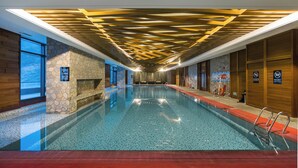 An indoor swimming pool with a stone wall, a wooden ceiling, and a red floor. - YunDing Grand Hotel (Zhangjiakou)