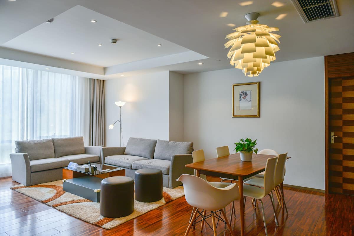 Una sala de estar moderna con un juego de sofá, una mesa de comedor con sillas, una mesa de centro y una lámpara de techo original.