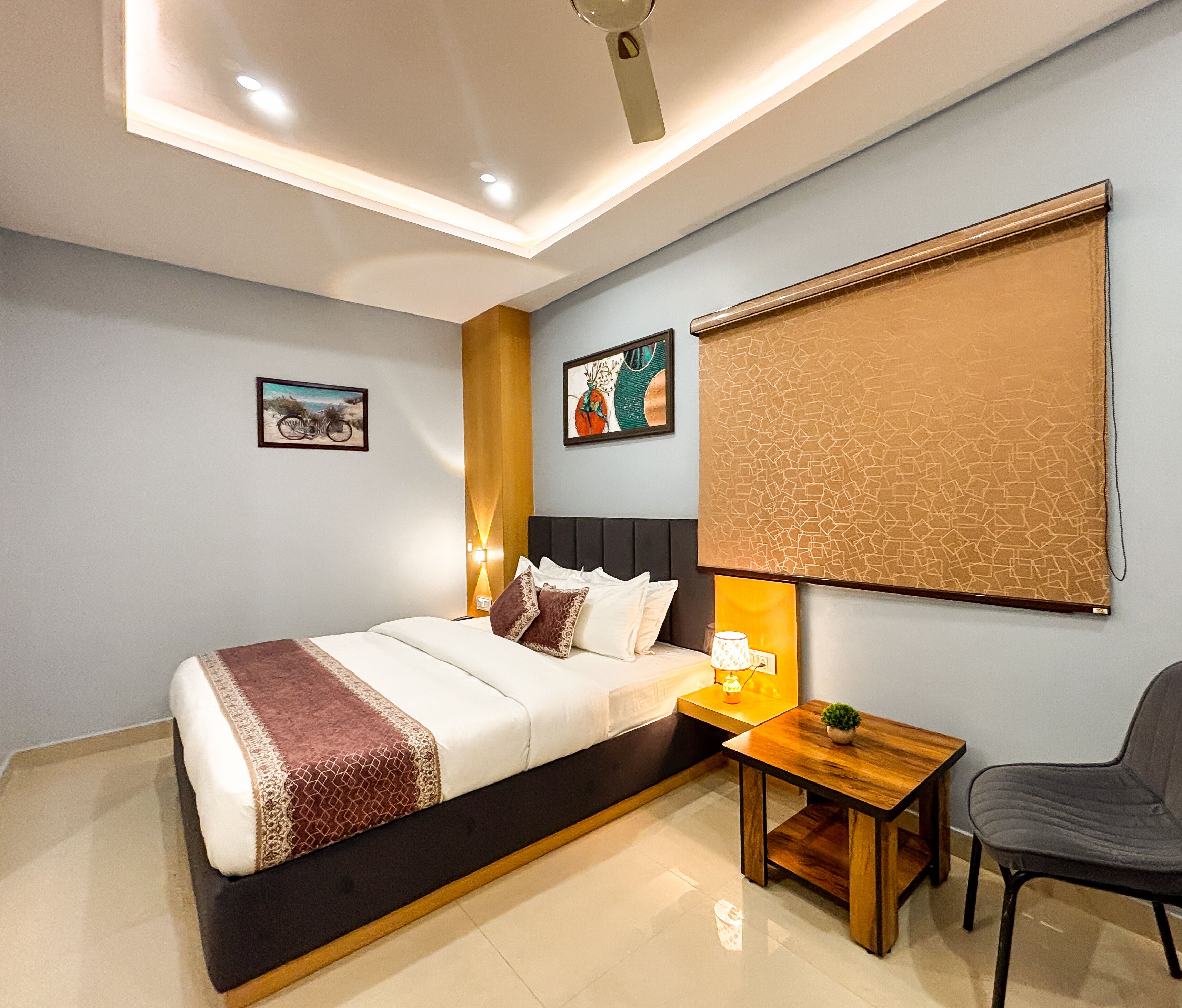 Un dormitorio moderno con una cama grande, mesitas de noche, una silla y obras de arte en las paredes.