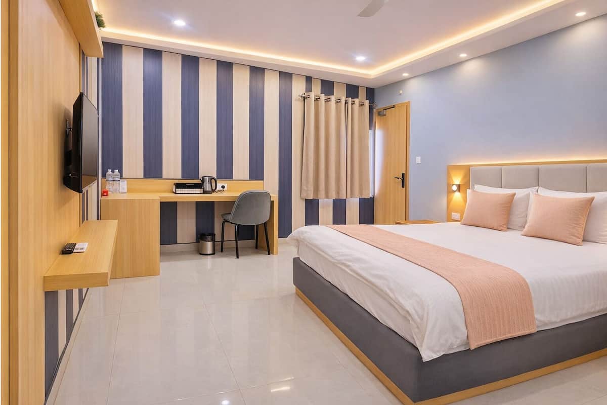 A modern hotel room with a large bed, a desk with a chair, a television, and a shower area.
