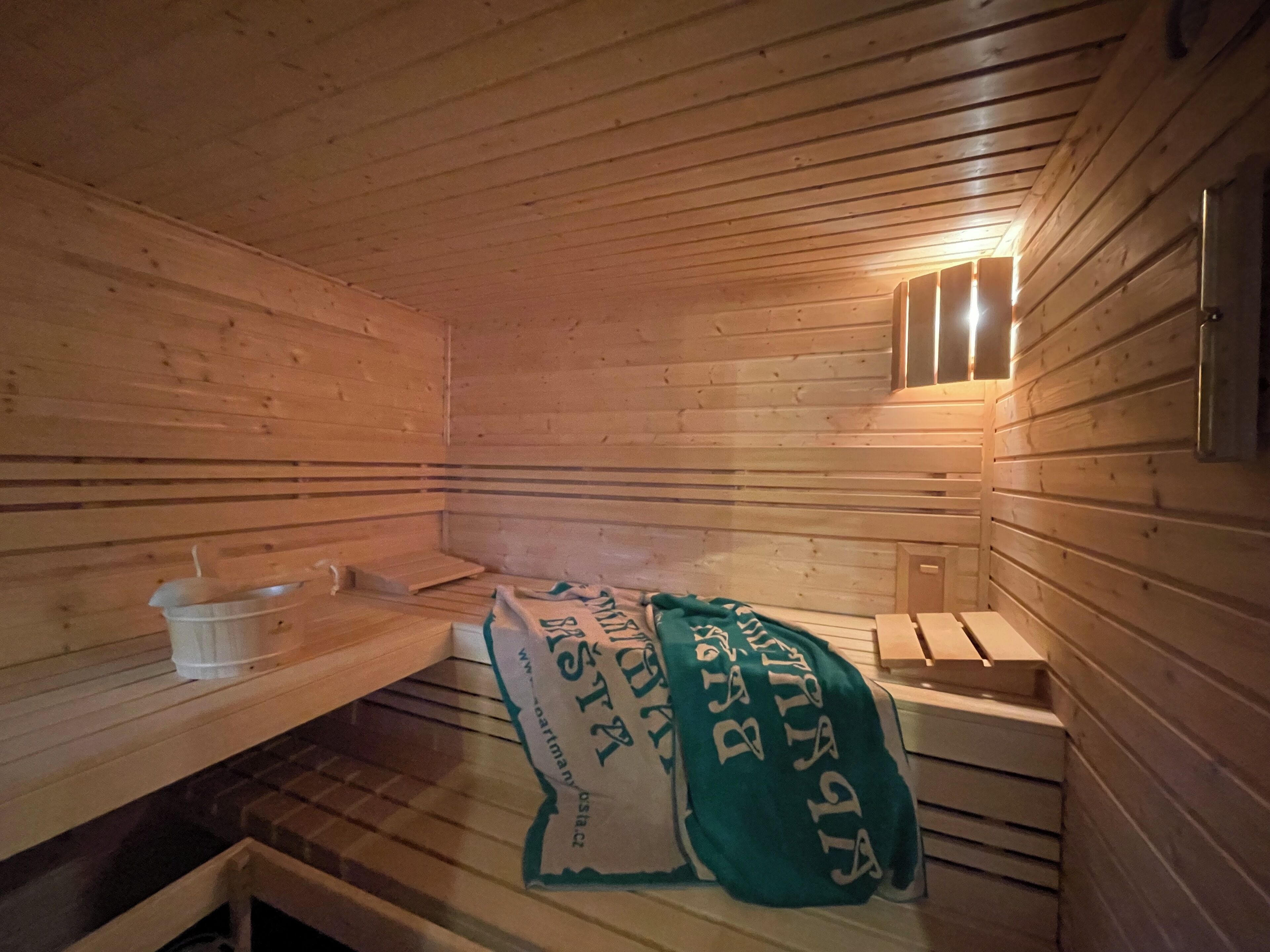A sauna with wooden walls and benches, a bench with a towel, and a small window.